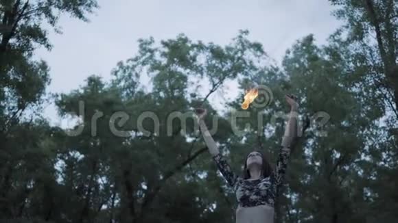 肖像可爱自信的女人表演一场表演火焰站在森林或公园有技巧的消防艺术家视频的预览图