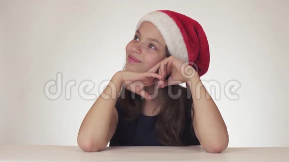 美丽快乐的少女戴着圣诞老人的帽子梦想着礼物收到节日蛋糕并表达不满视频的预览图