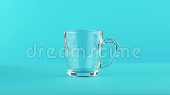4K近景拍摄的水果泡沫橙冷饮料可怜的玻璃杯与圆形手柄蓝色背景视频的预览图