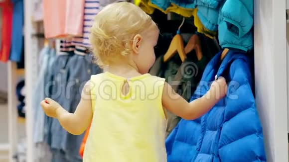 家庭购物时小女孩在儿童服装店里摸衣服视频的预览图