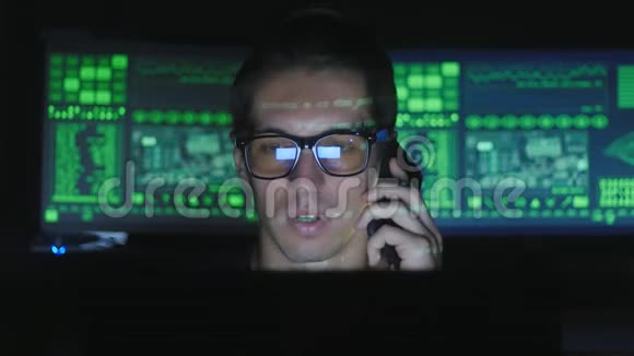 戴眼镜的黑客程序员正在网络安全中心用显示屏打电话视频的预览图