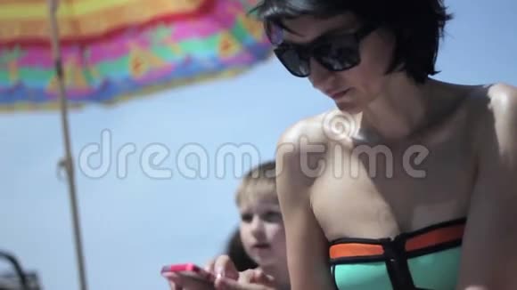 妈妈在海滩上使用智能手机视频的预览图