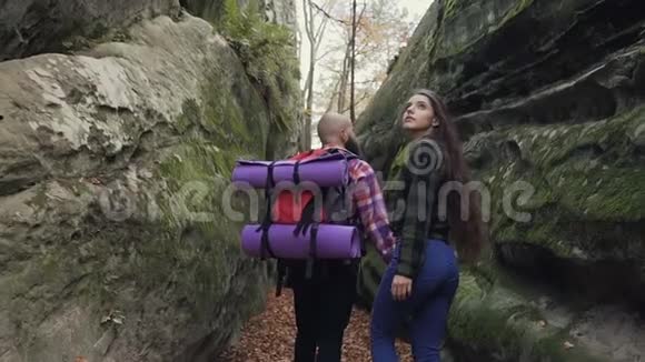 特写镜头在阳光明媚的日子里男人和女人背着背包走在岩石之间的人行小径上视频的预览图