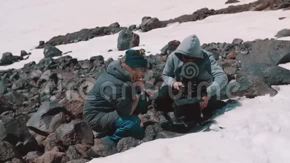 两名拍摄人员在雪山悬崖进行摄像调整视频的预览图