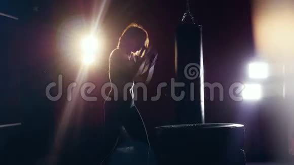 女性剪影做暗箱操作年轻女子在黑暗中拳击镜头耀斑视频的预览图