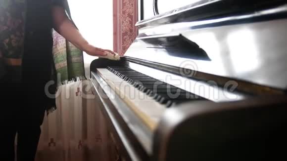 家中的老妇人用手擦去钢琴上的灰尘视频的预览图