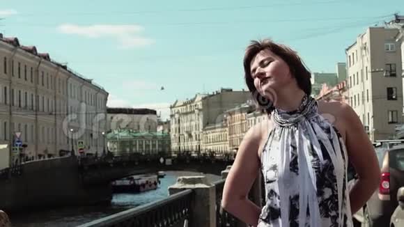 穿着斑点裙子的美女在老市中心的河边享受时光视频的预览图