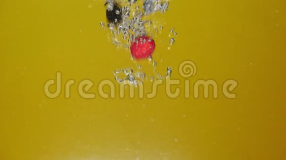 许多新鲜浆果在黄色背景下掉进水里视频的预览图