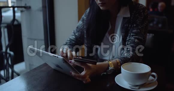 年轻女子在咖啡馆的平板电脑上做网上购物手的细节视频的预览图