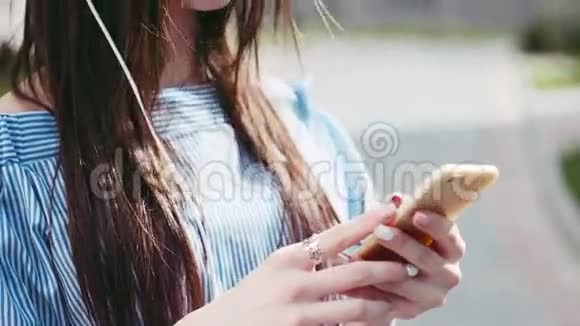 漂亮的年轻女子时髦的样子用手机打开音乐用白色耳机听音乐视频的预览图