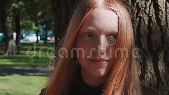 长发红发美女在公园树下微笑视频的预览图
