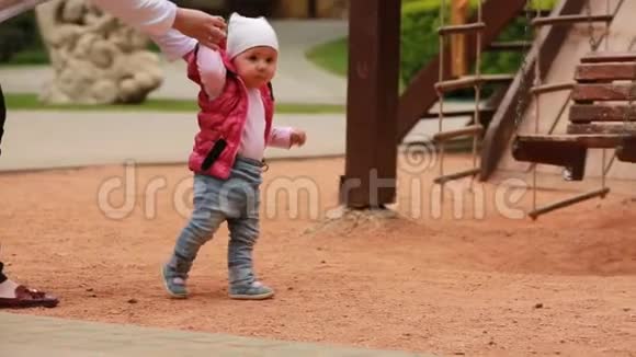 城市公园操场上小可爱女婴的第一步视频的预览图