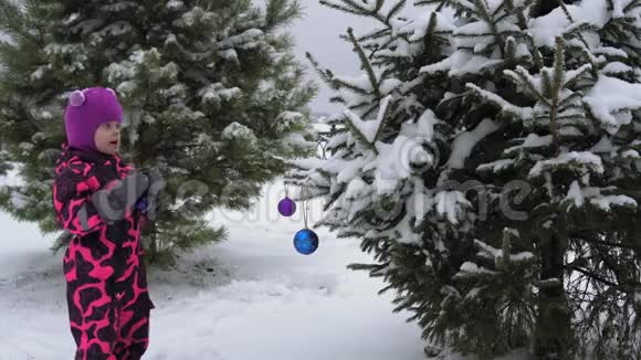 快乐的孩子在户外装饰一棵蓬松的圣诞树视频的预览图