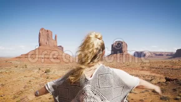妇女坐在纪念碑谷与红色岩石概述举起她的手臂视频的预览图