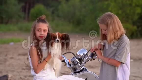 两个姐妹在一起玩得很开心两个女孩和一只狗在海边的摩托附近玩耍两个女孩在一起玩耍和交谈视频的预览图