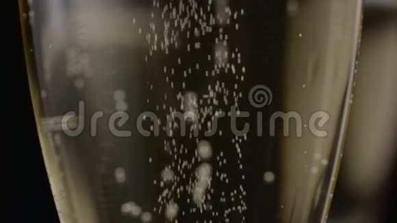 香槟的气泡从玻璃底部上升到顶部黑色背景关门视频的预览图