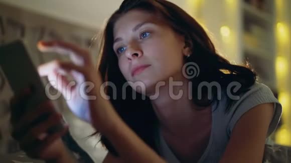 夜间躺在家里的年轻集中女性使用智能手机的特写镜头视频的预览图
