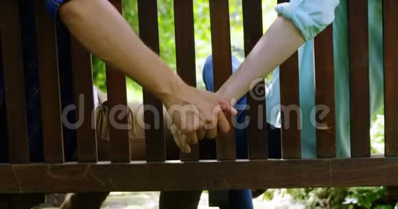 浪漫的情侣手牵手坐在公园的长椅上视频的预览图