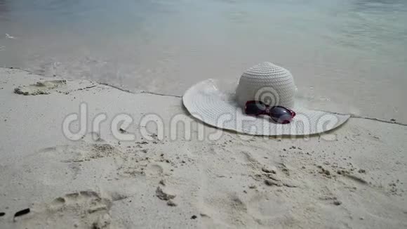 太阳镜和白色宽边躺在沙子上沙滩上有波浪的海景视频的预览图