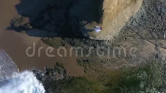 自由概念穿着白色连衣裙和围巾的女人站在岩石上跳舞在飞行从上面的空中摄影视频的预览图