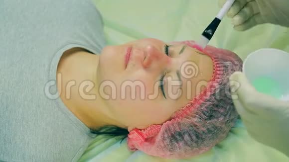 化妆师的男人的手在女人的脸上用刷子涂了一个液体面具视频的预览图