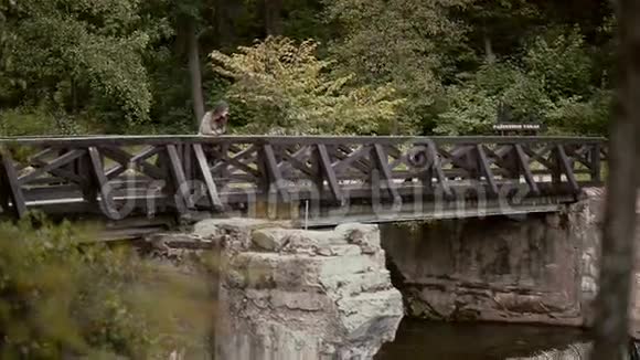 一位黑发迷人的年轻女子正倚在木桥的栏杆上怅然若失地望着水面视频的预览图