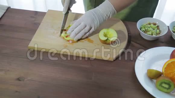 一个女人用刀子把苹果切成木板上的薄片摄像机从右向左移动视频的预览图
