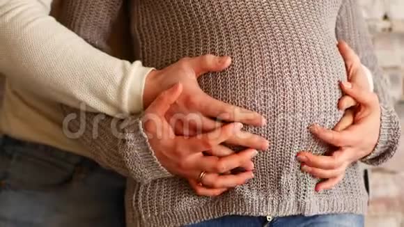 妈妈和爸爸手在怀孕的肚子上显示心脏的迹象怀孕夫妇抚摸怀孕的肚子准妈妈照顾视频的预览图