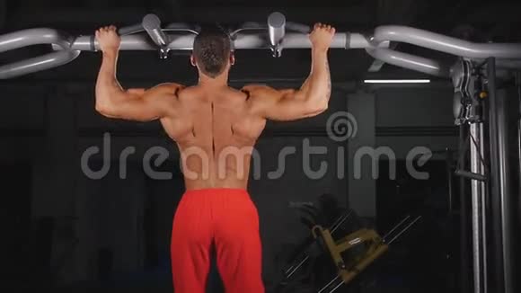 在健身房酒吧锻炼的运动员的后视角视频的预览图