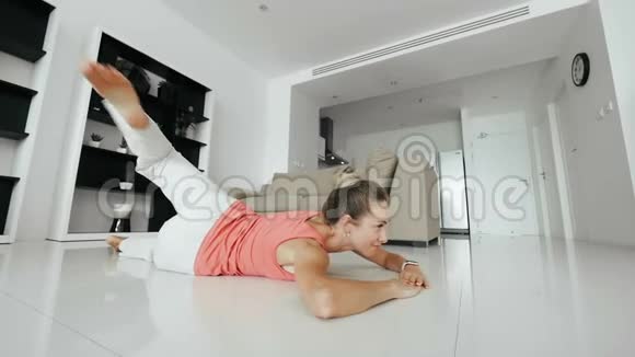 美丽的女人躺在地板上做健身运动在家里养腿视频的预览图
