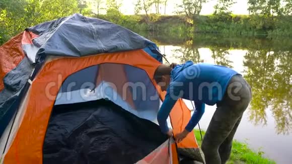 女人正在河岸上搭旅游帐篷视频的预览图