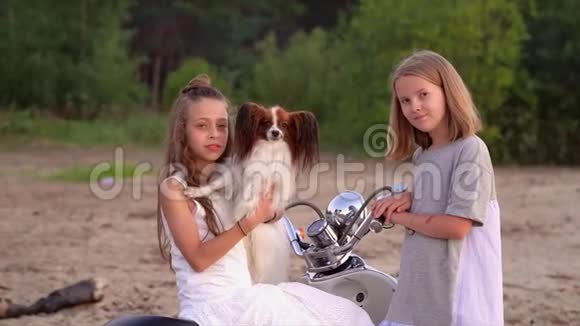 两个姐妹在一起玩得很开心两个女孩和一只狗在海边的摩托附近玩耍视频的预览图