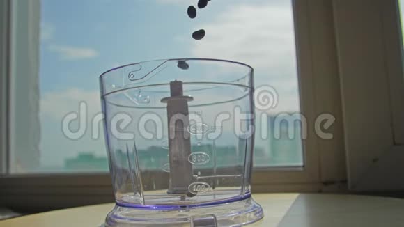 慢动作新鲜的烤咖啡豆从玻璃罐里倒入磨床视频的预览图