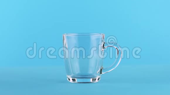 牛奶冷饮饮料的慢速特写镜头用圆形手柄蓝底调成玻璃杯视频的预览图