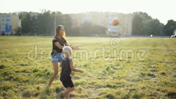 妈妈和小孩子在美丽的日落草地上玩球视频的预览图