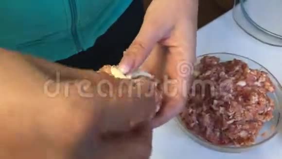 一个女人用膨松的糕点条包裹碎肉丸桌子旁边放着几条酥皮还有一个剁碎的视频的预览图