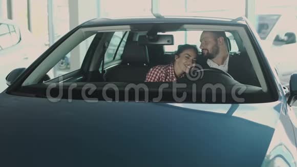 幸福的一对夫妇坐在现代化的汽车上在汽车陈列室享受新的购买视频的预览图