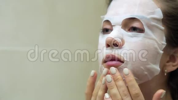 关闭年轻女人做面膜年轻的女人做一个美容面膜护肤护肤用化妆品面膜视频的预览图