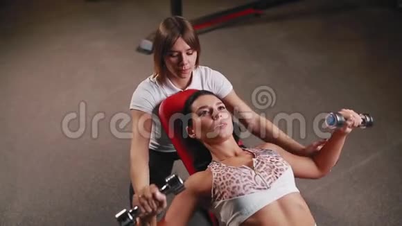 她和她的私人健身教练在健身房锻炼哑铃视频的预览图