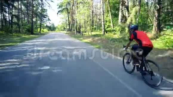 在一个寒冷的日子里年轻人骑着自行车在森林道路上视频的预览图
