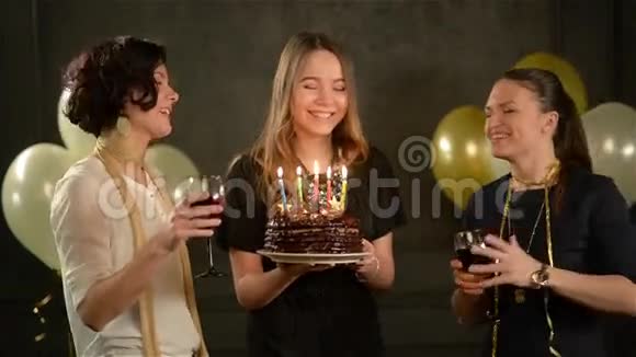 年轻漂亮的女人许愿吹灭巧克力蛋糕上的蜡烛两个微笑的女人眨眼睛视频的预览图