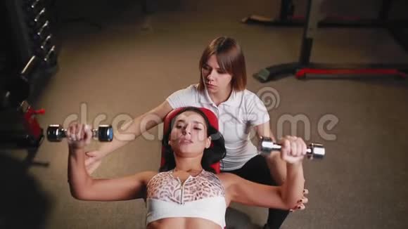 她和她的私人健身教练在健身房锻炼哑铃视频的预览图