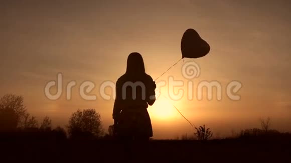 日落时带气球的年轻女子剪影视频的预览图