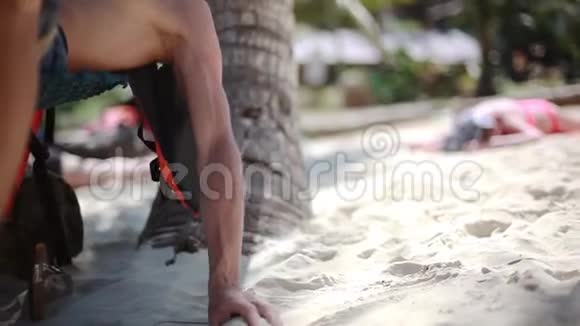 年轻的帅哥戴着太阳镜在美丽的热带海滩上的吊床上放松手上的沙子从他的手中滑落视频的预览图