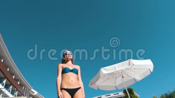 在蓝天和酒店背景下穿泳衣的女孩视频的预览图