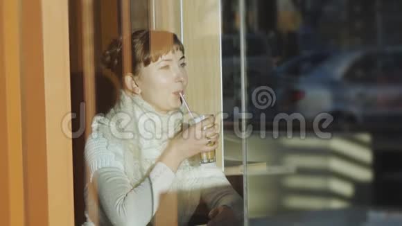 年轻女子在咖啡馆喝咖啡白种人妇女带着蕾丝羊毛围巾微笑着喝着拿铁的肖像视频的预览图
