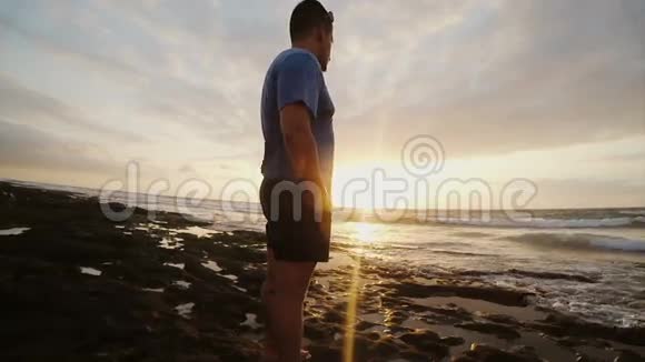 海滩上的人看着美丽的日落男人看着远方的地平线和思考喜欢海景视频的预览图