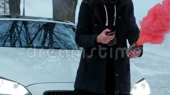 一个穿黑色夹克的年轻人在一辆昂贵的白车背景下读饶舌歌红色的烟雾产生了强烈的效果视频的预览图