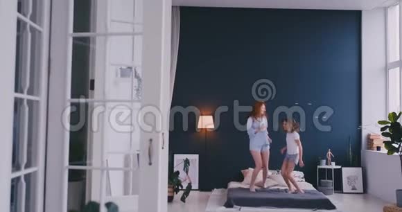 母亲和女儿在床上跳跃快乐快乐视频的预览图