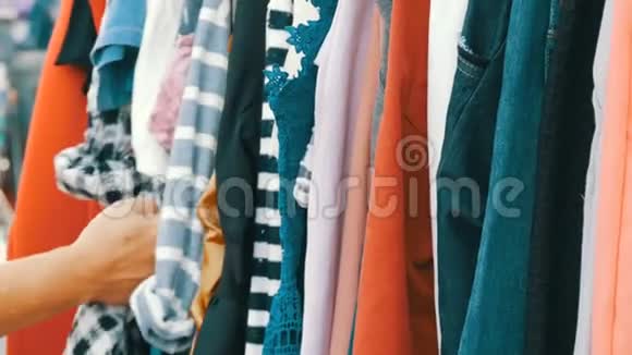 东西挂在衣架上女人手看衣服选择跳蚤市场市场上出售的衣服视频的预览图
